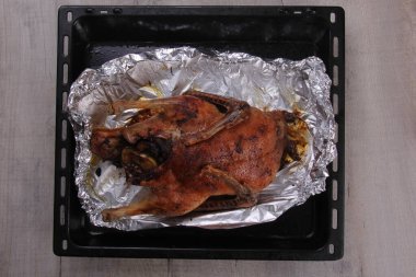 Fırın tepsisi ve alüminyum folyoyla doldurulmuş Noel ördeği rostosu.