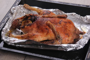 Fırın tepsisi ve alüminyum folyoyla doldurulmuş Noel ördeği rostosu.