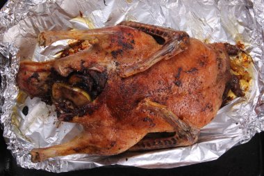 Fırın tepsisi ve alüminyum folyoyla doldurulmuş Noel ördeği rostosu.