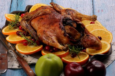 Taze biberiyeli bütün ördek, kil tabakta portakal, eski mavi ahşap tahta arka plan, doldurulmuş ördek rostosu.