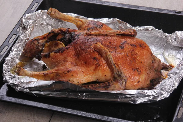 Fırın tepsisi ve alüminyum folyoyla doldurulmuş Noel ördeği rostosu.
