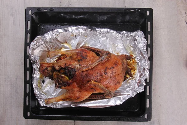 Fırın tepsisi ve alüminyum folyoyla doldurulmuş Noel ördeği rostosu.