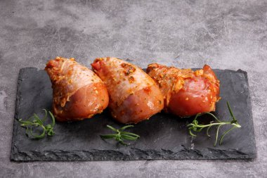 Siyah taş tabakta marine edilmiş çiğ tavuk bacağı. Pişmemiş marine edilmemiş tavuk.