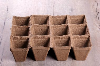 Gri ahşap arka planda boş turba kapları. Fidanlar için turba kapları