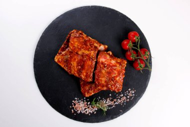 Çiğ domuz pirzolası, siyah taş tabakta pişirilmeye hazır. Çiğ bbq kaburga, ızgara için marine edilmiş et, kemikli et.