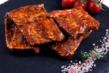 Çiğ domuz pirzolası, siyah taş tabakta pişirilmeye hazır. Çiğ bbq kaburga, ızgara için marine edilmiş et, kemikli et.