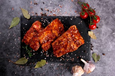 Çiğ domuz pirzolası, siyah taş tabakta pişirilmeye hazır. Çiğ bbq kaburga, ızgara için marine edilmiş et, kemikli et.