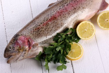 Beyaz ahşap arka planda Gökkuşağı alabalığı balığı. Limon ve baharatlı çiğ alabalık.