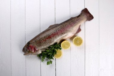 Beyaz ahşap arka planda Gökkuşağı alabalığı balığı. Limon ve baharatlı çiğ alabalık.