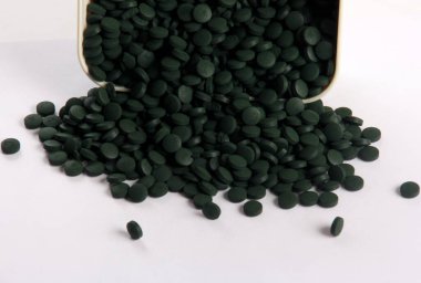 Beyaz arkaplanlı, yeşil haplar. Sağlıklı süper gıda diyeti ve detoks beslenme konsepti 