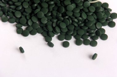 Beyaz arkaplanlı, yeşil haplar. Sağlıklı süper gıda diyeti ve detoks beslenme konsepti 