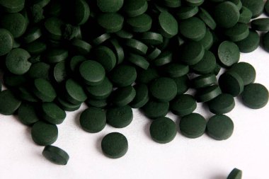 Beyaz arkaplanlı, yeşil haplar. Sağlıklı süper gıda diyeti ve detoks beslenme konsepti 