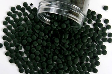 Beyaz arkaplanlı, yeşil haplar. Sağlıklı süper gıda diyeti ve detoks beslenme konsepti 