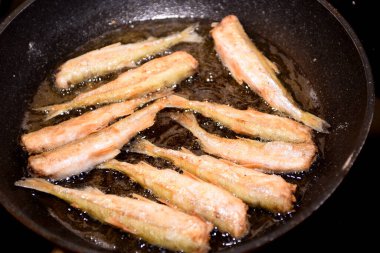 Siyah bir mutfak tavasında kıtır ekmekli Avrupa eritilmiş balığı (Osmerus eperlanus). Tavada küçük balık kızartması.