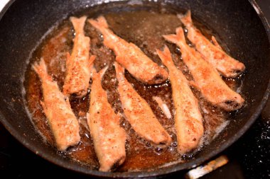 Siyah bir mutfak tavasında kıtır ekmekli Avrupa eritilmiş balığı (Osmerus eperlanus). Tavada küçük balık kızartması.