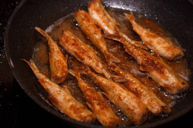 Siyah bir mutfak tavasında kıtır ekmekli Avrupa eritilmiş balığı (Osmerus eperlanus). Tavada küçük balık kızartması.