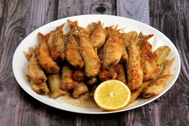 Taze limonlu ekmek kırıntılarıyla küçük kızarmış balık. Ekmek içinde kızarmış küçük balık, tabakta yakın plan. Yukarıdan yatay görünüm 