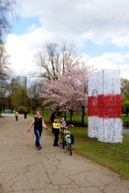 Riga, Letonya - Mayıs 05, 2021: İnsanlar Riga, Letonya 'daki Zafer Parkı' nda (Uzvaras parkları) kiraz sakura çiçekleri arasında yürüyüp dinleniyorlar.