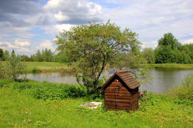 Göletin yanındaki çiftlikte ahşap tütsü evi. Kırsaldaki ahşap tütsü evi. Ev yapımı et içiyorum.