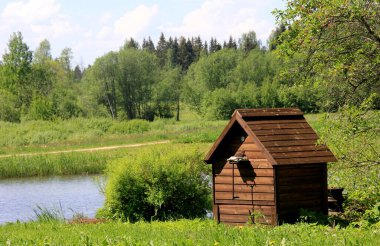 Göletin yanındaki çiftlikte ahşap tütsü evi. Kırsaldaki ahşap tütsü evi. Ev yapımı et içiyorum.