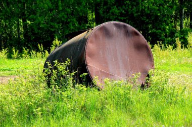 Su için büyük metal fıçı. Bahçede metal bir su varili duruyor. Tarım tarlasında eski paslı bir varil. 
