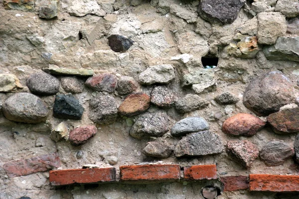 Old crumbling masonry wall with red bricks and stones.Old red brick wall, grunge background.Old crumbling red brick masonry close up