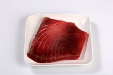 raw marble tuna steak in white plate isolated on white background, top view