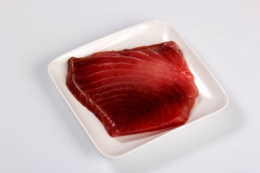 raw marble tuna steak in white plate isolated on white background, top view