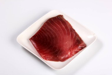 raw marble tuna steak in white plate isolated on white background, top view