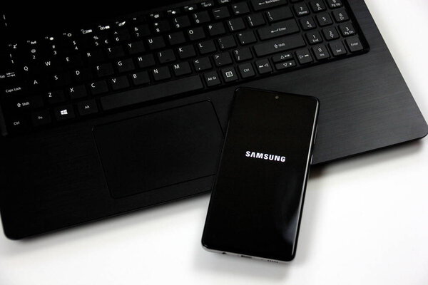 Рига, Латвия - 17 июня 2021 года: Фотография смартфона Samsung Galaxy A71 Android с логотипом андроида на черном ноутбуке. Обновление программного обеспечения на смартфоне Android