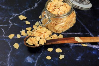 Dried garlic flakes on dark blue marble background. Dried vegetables