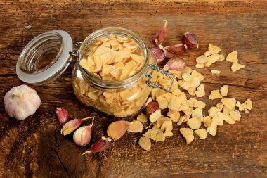 Dried garlic flakes on old wooden plank background. Dried vegetables