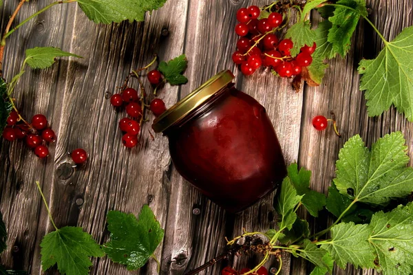 ベリージャムやソースとガラス瓶 木の板を背景に緑の葉を持つ赤スグリの枝 — ストック写真