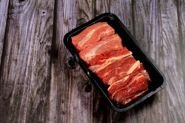 Siyah plastik bir kapta çiğ et. Çiğ etle açılmış siyah plastik tepsi