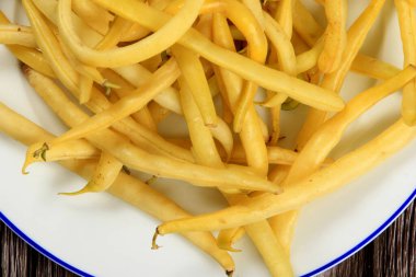 Koyu tahta arka planda taze sarı çalı fasulyesi. Çiftçi pazarından organik sebzeler, vejetaryen gıda kavramı. Taze tereyağlı fasulye. 