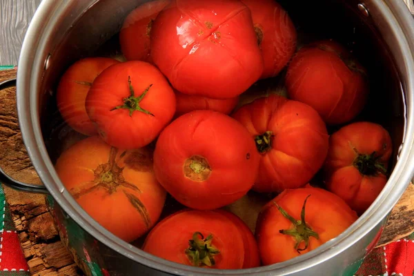 Red ripe tomatoes in a pot of hot water. Boiled Tomatoes. tomatoes poached in boiling water