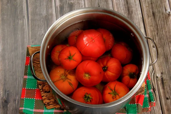 Red ripe tomatoes in a pot of hot water. Boiled Tomatoes. tomatoes poached in boiling water