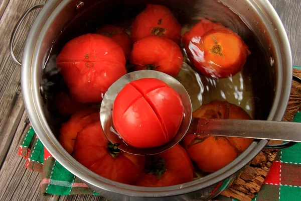 Red ripe tomatoes in a pot of hot water. Boiled Tomatoes. tomatoes poached in boiling water