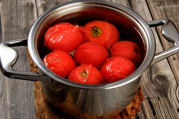 Red ripe tomatoes in a pot of hot water. Boiled Tomatoes. tomatoes poached in boiling water