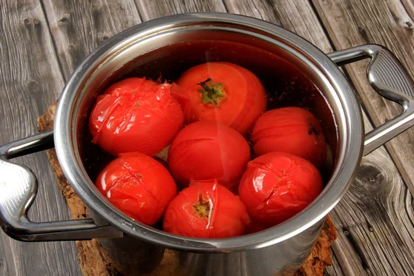 Red ripe tomatoes in a pot of hot water. Boiled Tomatoes. tomatoes poached in boiling water