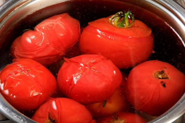 Red ripe tomatoes in a pot of hot water. Boiled Tomatoes. tomatoes poached in boiling water