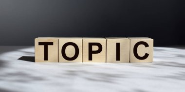 Tahta küplerdeki TOPIC yazıları karanlık bir arkaplanda izole edilmiş, iş ve finans kavramı.