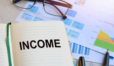 Ofis işyerinde, arkaplanda bir not defteri ve ahşap bir masanın üzerinde iş grafikleri var. İş konsepti çalışma alanı.