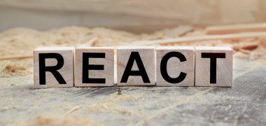 REACT kelimesi tahta küplere yazılır. Açık havada tahta küpler, kırsal alana tepeden bakan. İşle ilgili tasarım için. Pazarlama kavramı.