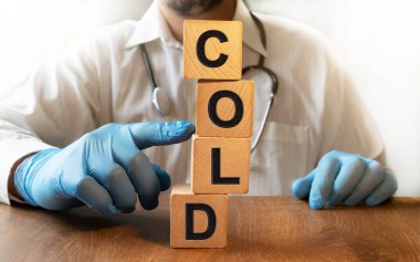 Tahta küplere yazılan soğuk yazı. Tıbbi eldivenli bir erkek doktor küpleri itiyor. Sağlık ve Tıp Konsepti.