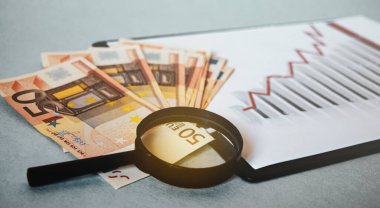 Avro banknotları yakın plan, büyüteç, grafiklerin arka planında.