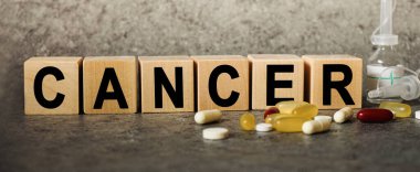 Harfli bir metin olarak CANCER, metin için boşluk ile koyu gri arkaplan üzerinde kelime küpleri ile corona virüsü salgını.