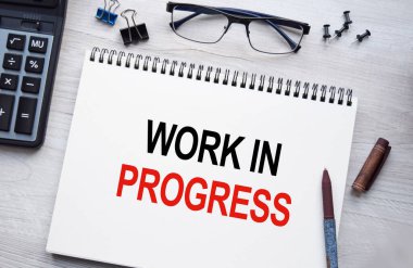 Progresdeki yazıtların olduğu not defteri. Kavramsal görüntü, iş aksesuarları, masaüstünde izole edilmiş hesap makinesi. Finans ya da iş konsepti.