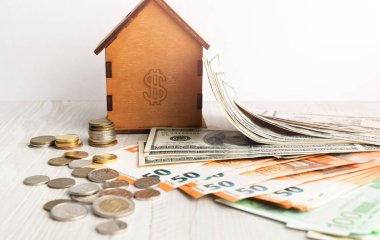 Ev, banknotlar ve manetlerle birlikte masada. Ev, emlak konsepti, ipotek ve gayrimenkul yatırımı almak için madeni para tasarrufu planlaması. Bir ev almak için..
