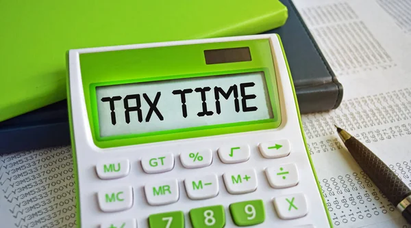 緑の計算機はデスクトップにあります Tax Timeという言葉は計算機に書かれています グラフや財務表と一緒に 財務又は事業の概念 — ストック写真